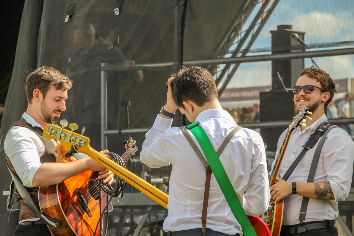 Antony, Jamie and Fergus together on an outdoor stage with their instruments