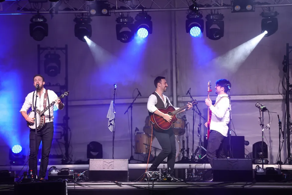 Fergus singing on banjo while Antony and Jamie share a smile on stage