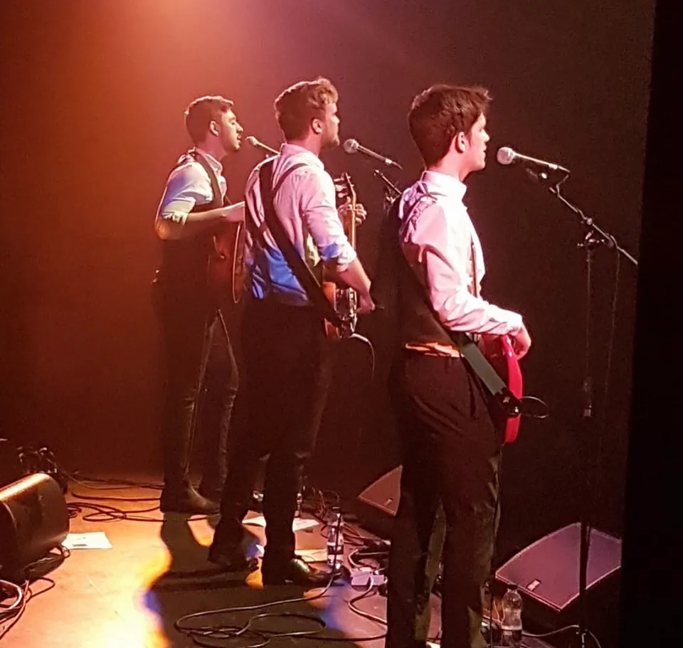 Antony, Fergus and Jamie performing together under red stage lights