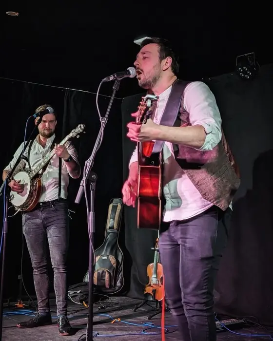 Fergus and Antony on stage, a fiddle waiting on its stand