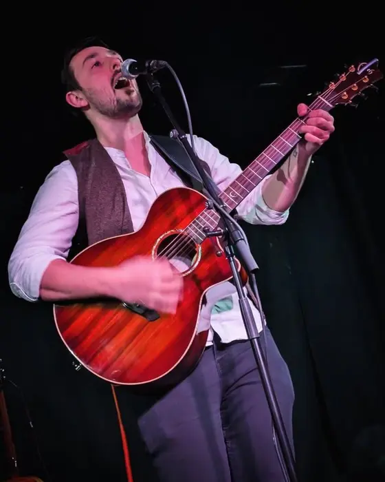 Antony singing under purple stage lights